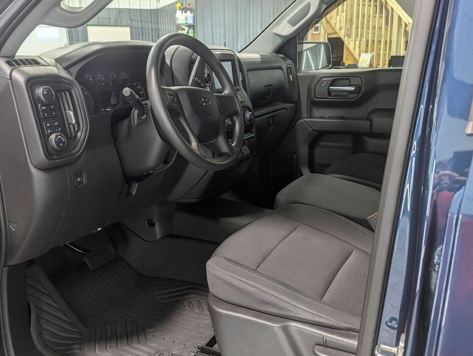 The interior of a blue truck with the door open and the steering wheel visible.