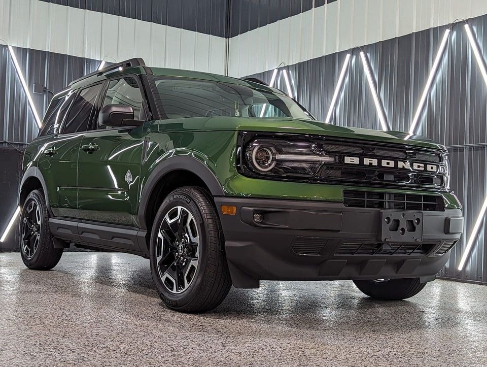 A green ford bronco sport is parked in a showroom.