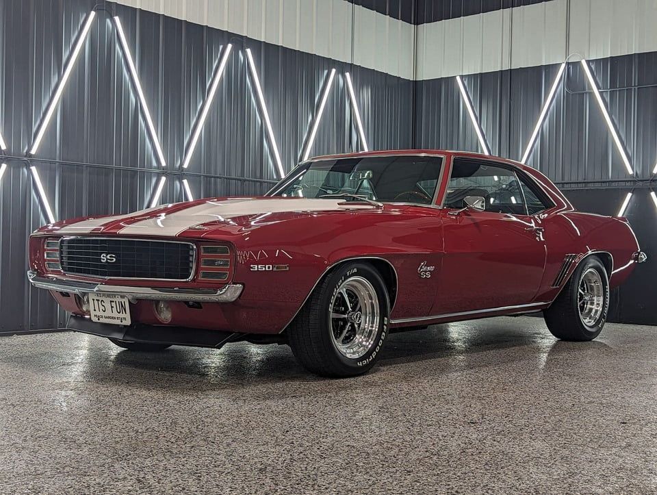 A red chevrolet camaro is parked in a garage.