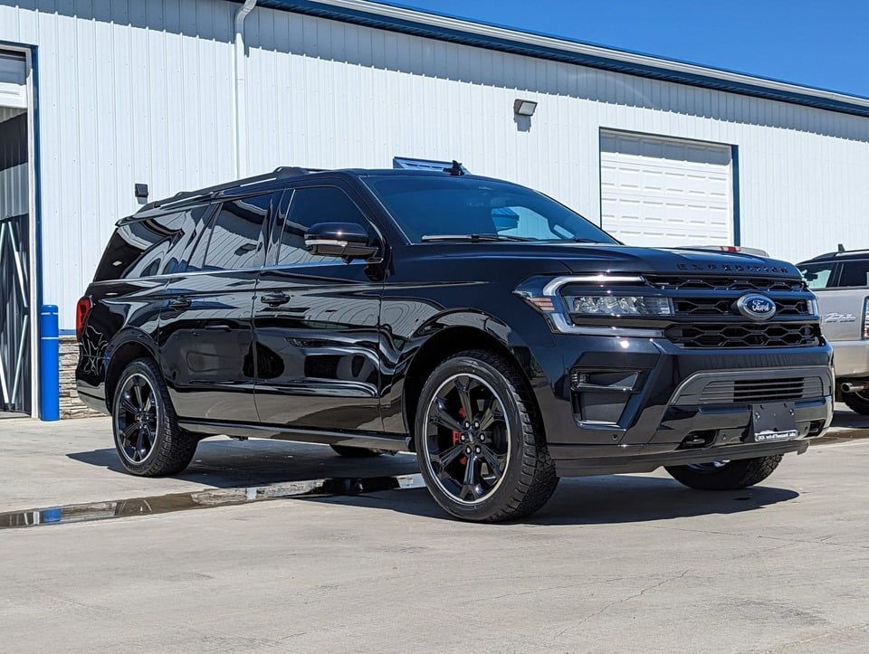 A black ford expedition is parked in front of a white building.