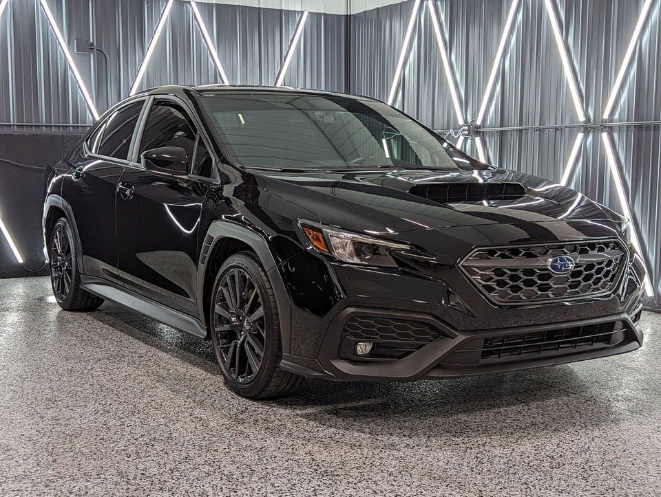 Black Subaru WRX, parked inside a showroom with patterned lighting.