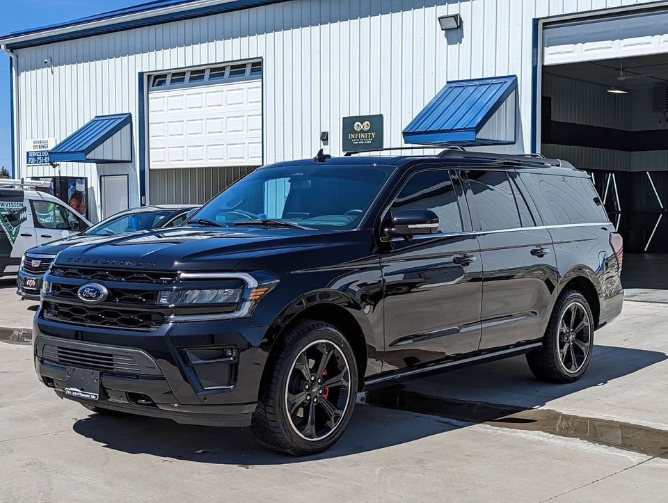 A black ford expedition is parked in front of a building.
