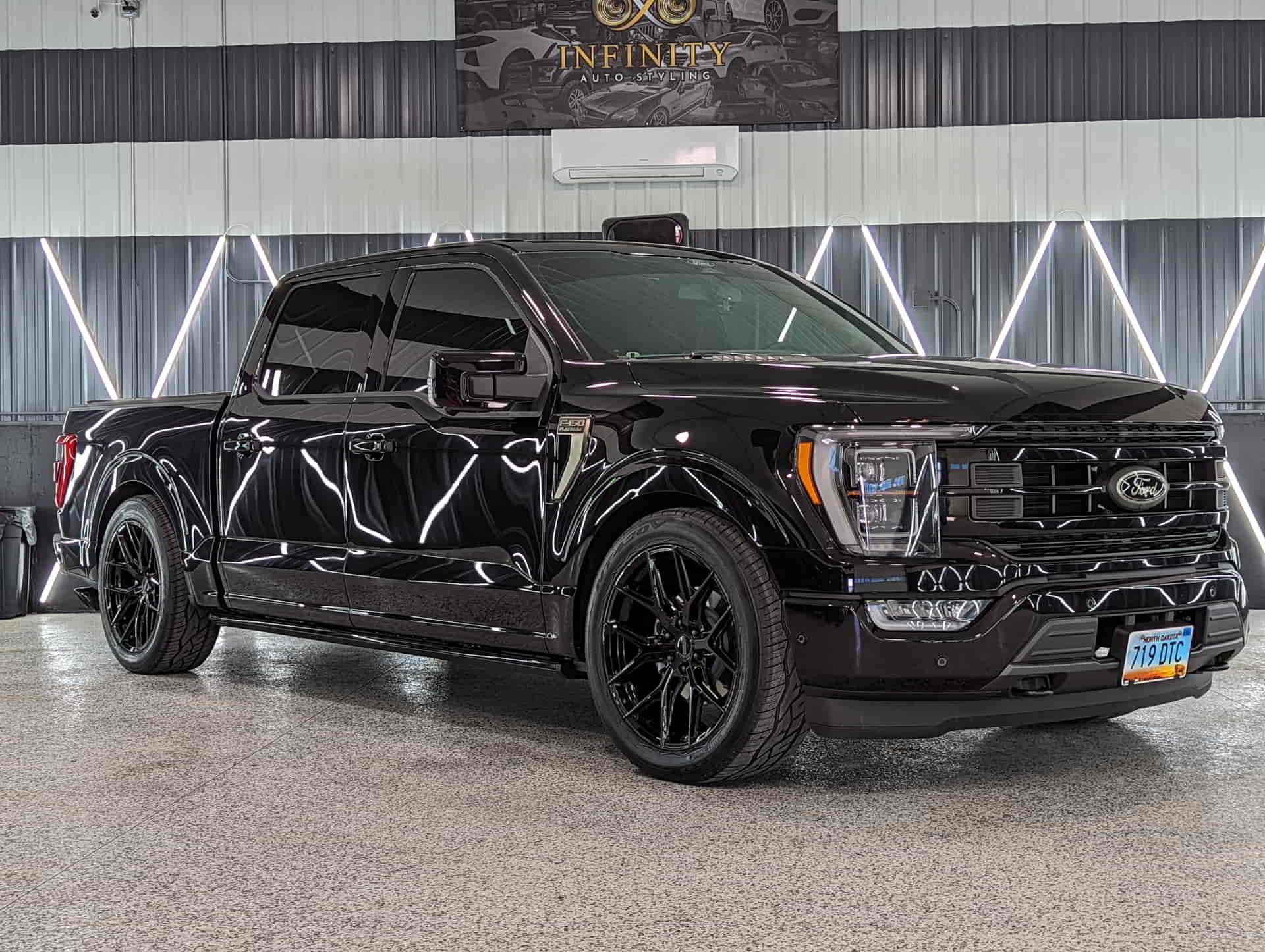 A black ford f150 truck is parked in a garage.