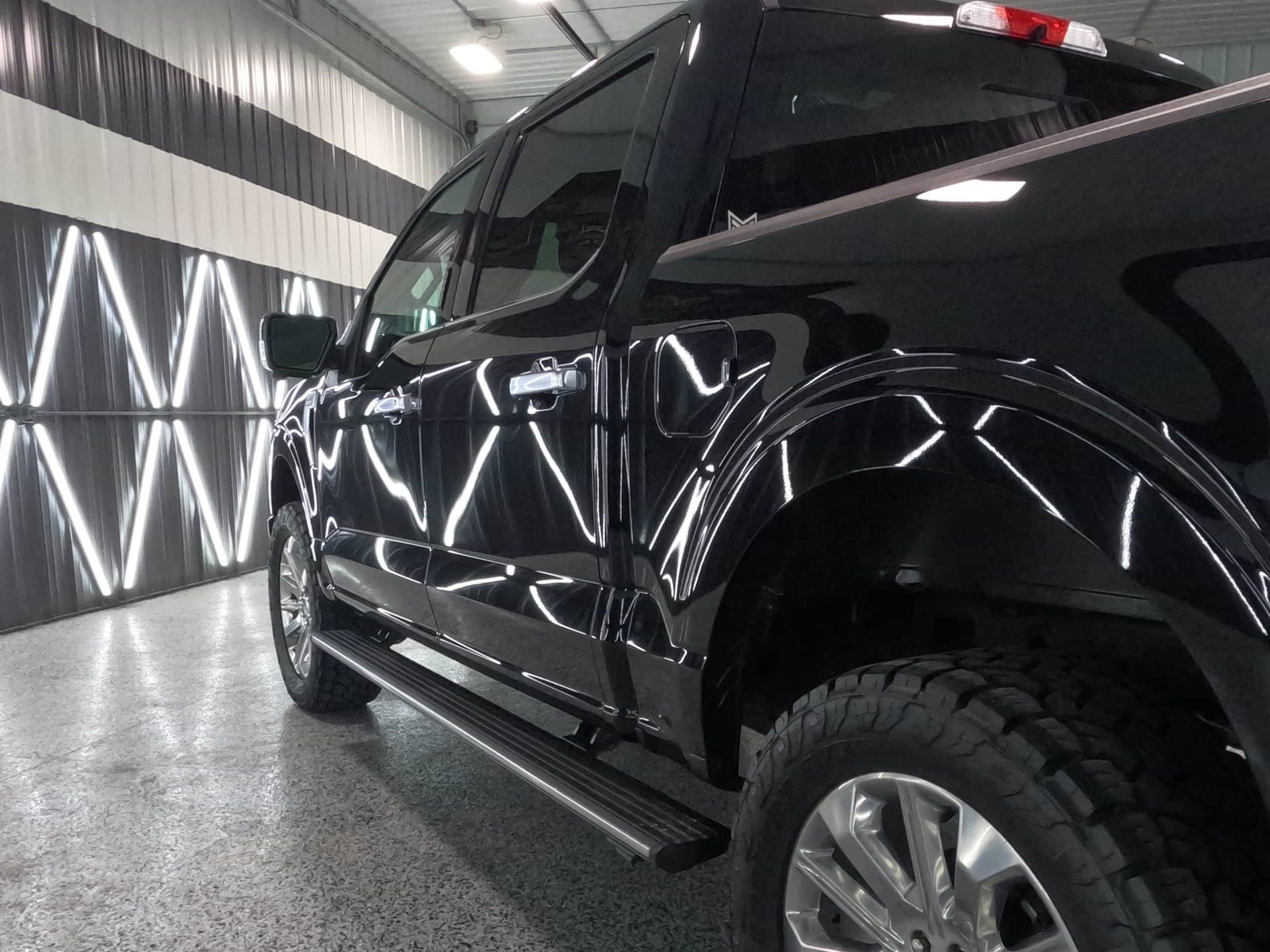 A black pickup truck is parked in a garage.