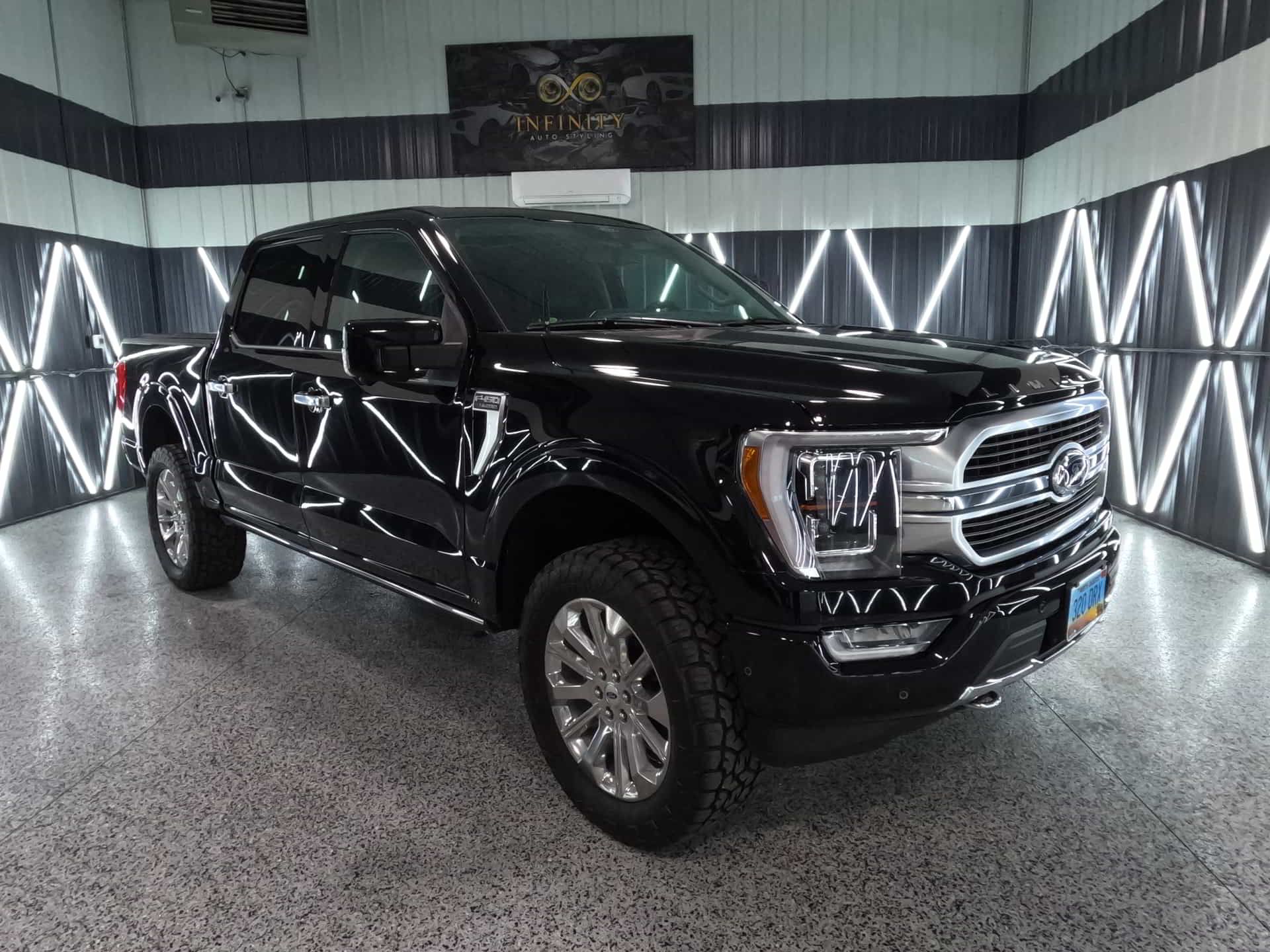 A black ford f150 is parked in a garage.