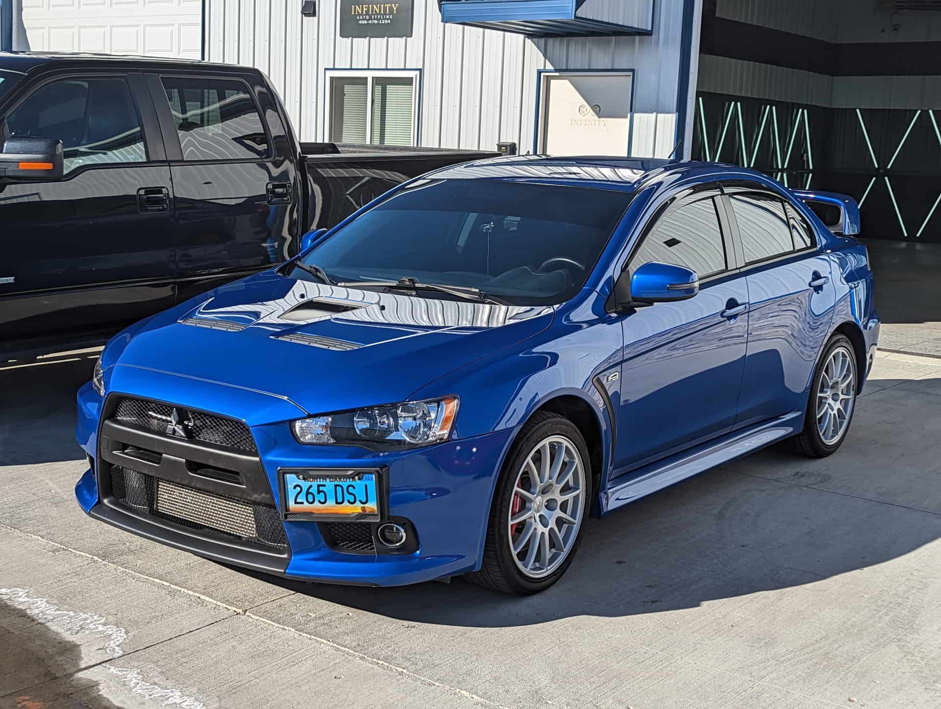 A blue mitsubishi lancer evo is parked in front of a building.