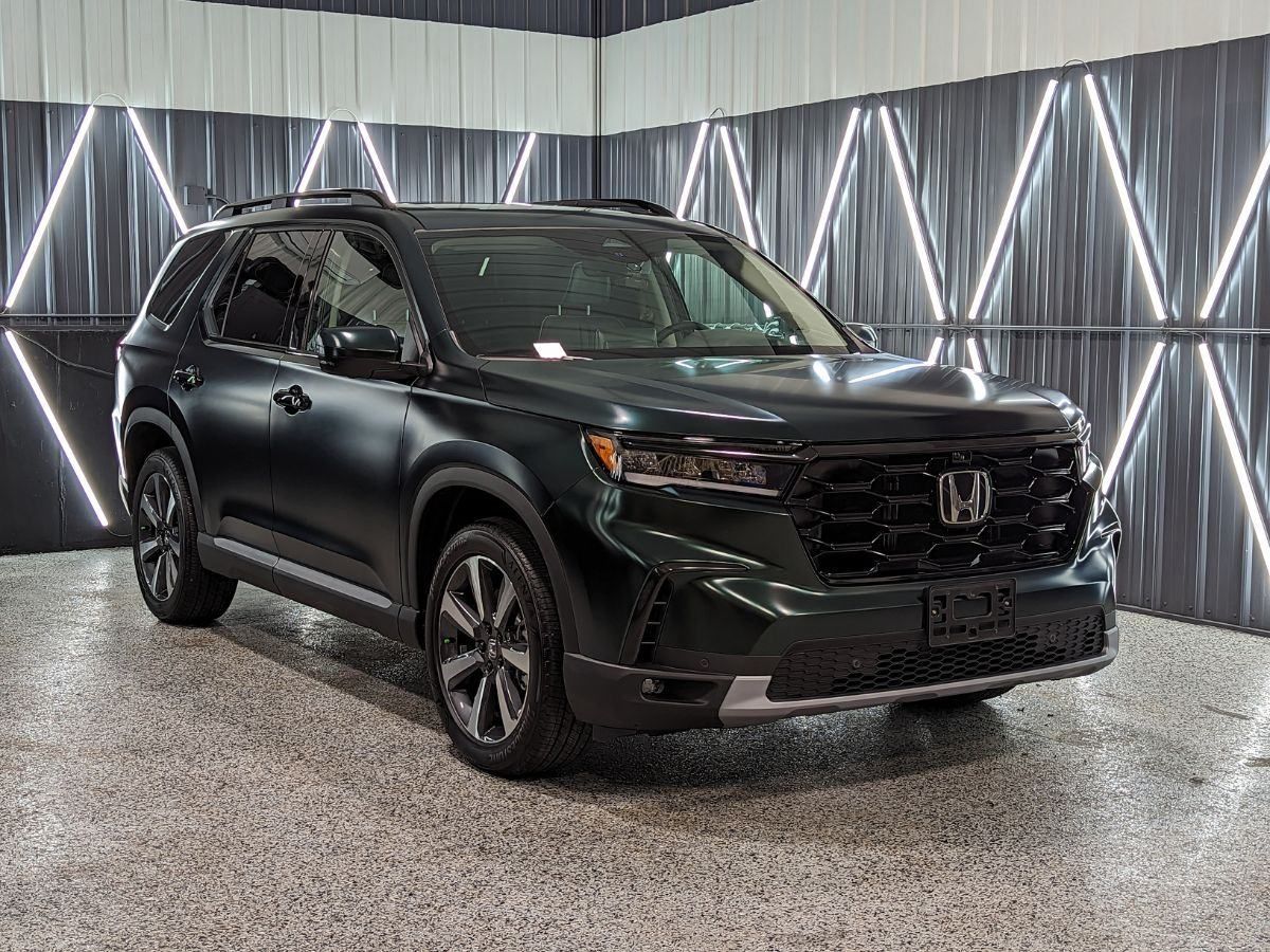 A black honda pilot is parked in a showroom.