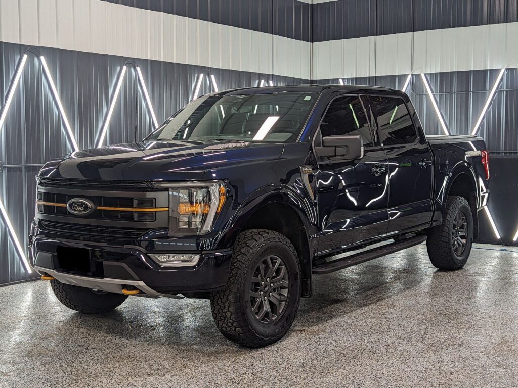 A black ford f150 truck is parked in a garage.