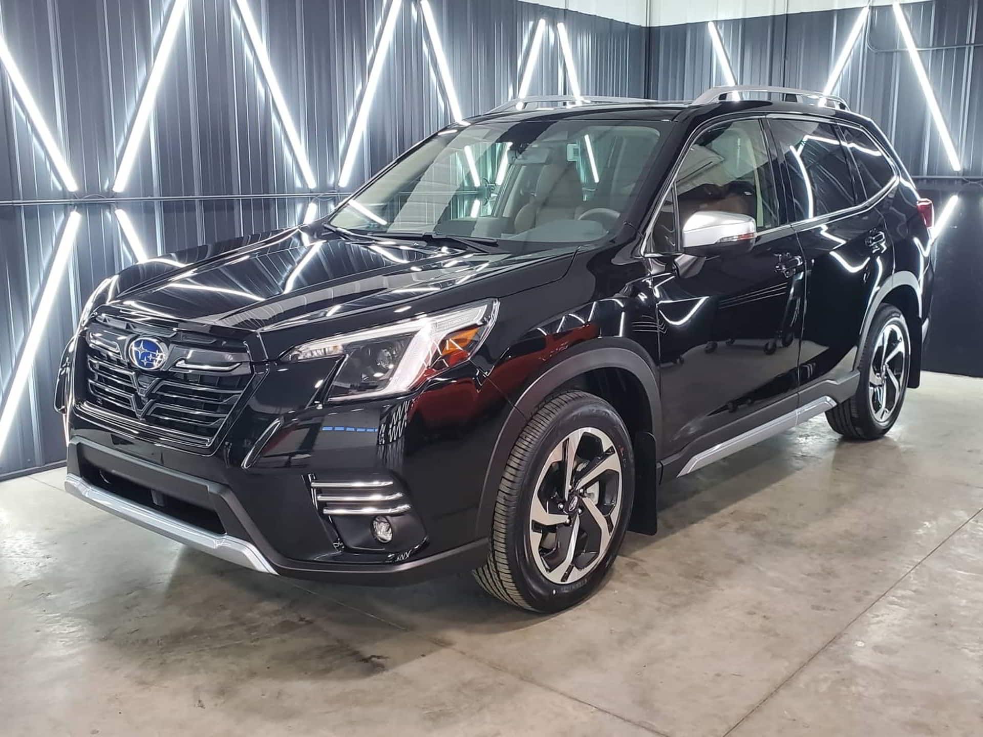 A black subaru forester is parked in a showroom.