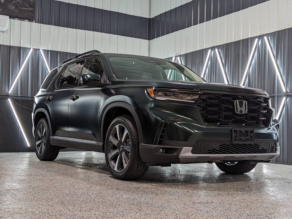 A black honda ridgeline is parked in a garage.