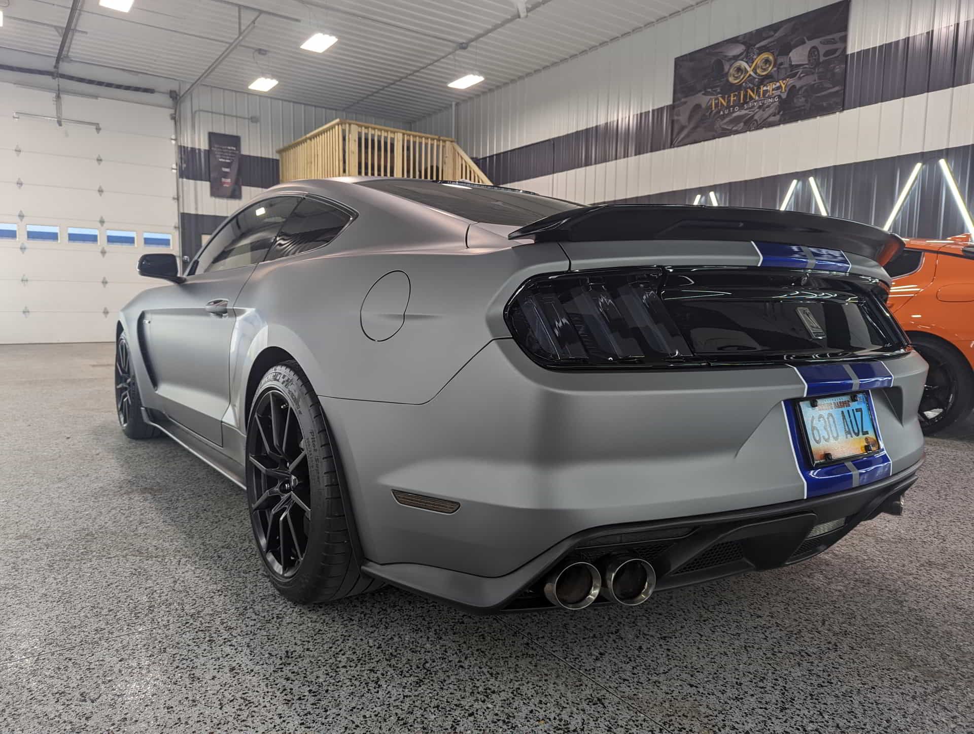 A gray mustang is parked in a garage.