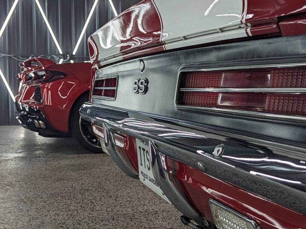 A red and white car is parked next to another car in a garage.