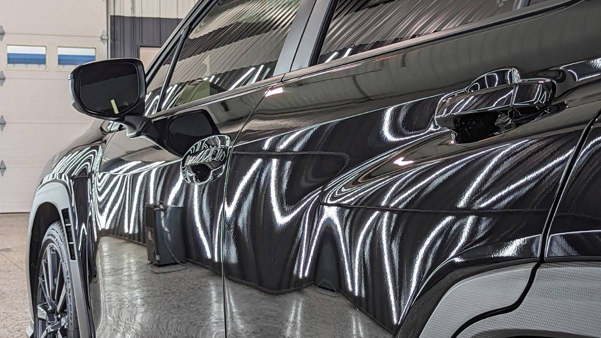 A black car is parked in a garage in front of a garage door.