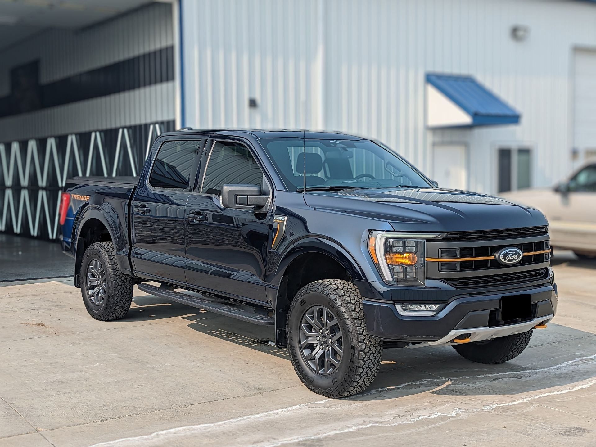 A black ford f150 truck is parked in a parking lot in front of a building.