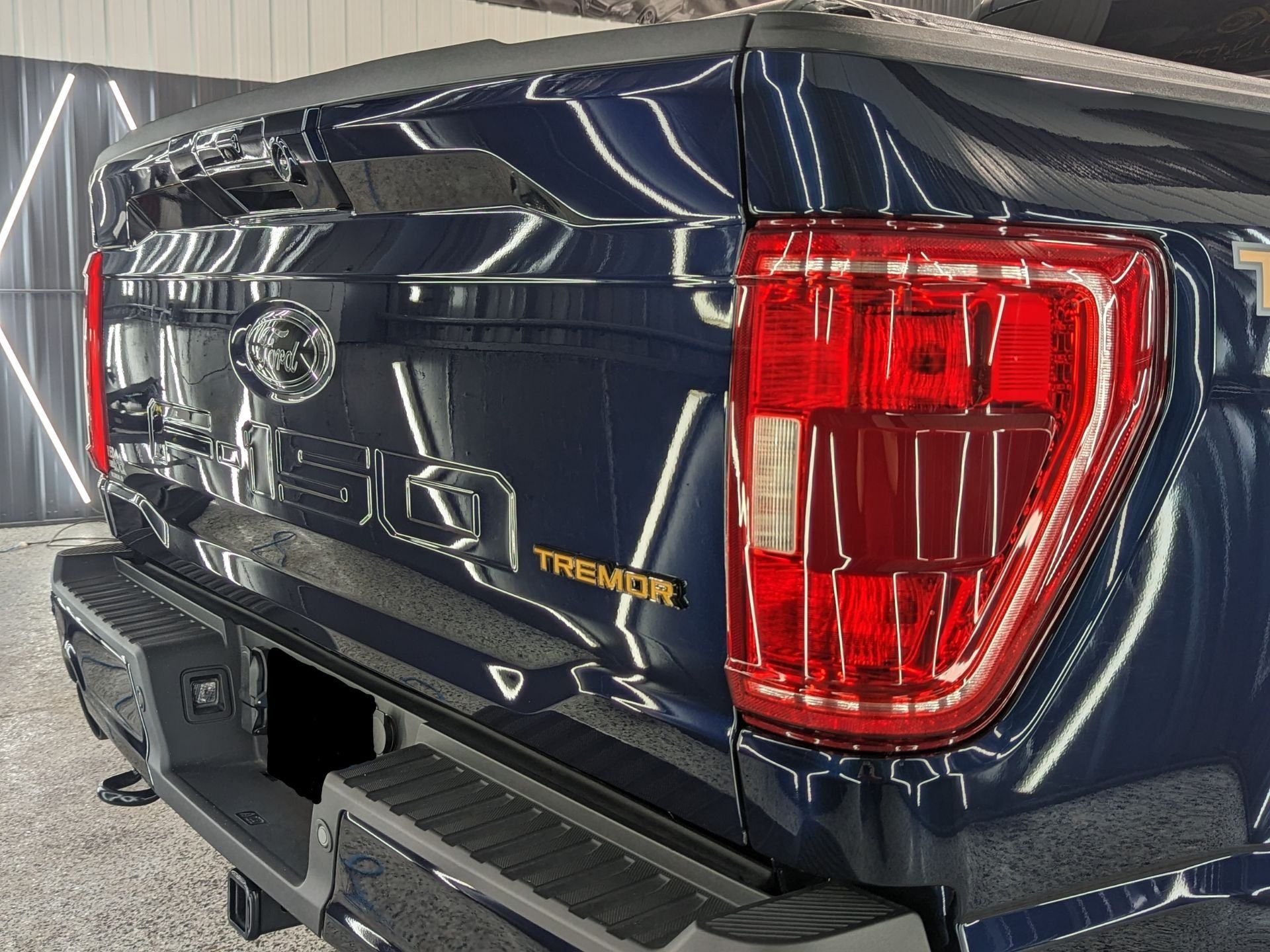 A blue truck with a red tail light is parked in a garage.