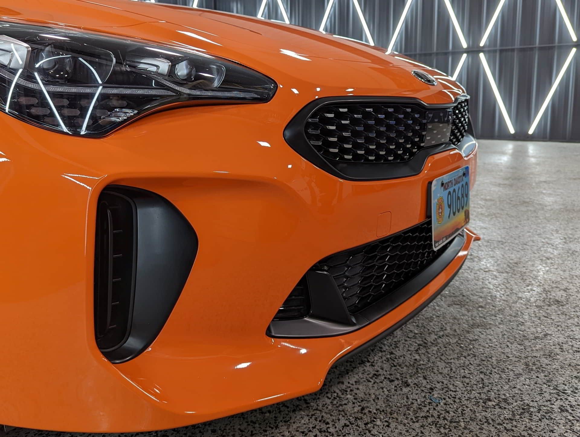 A close up of the front of an orange car