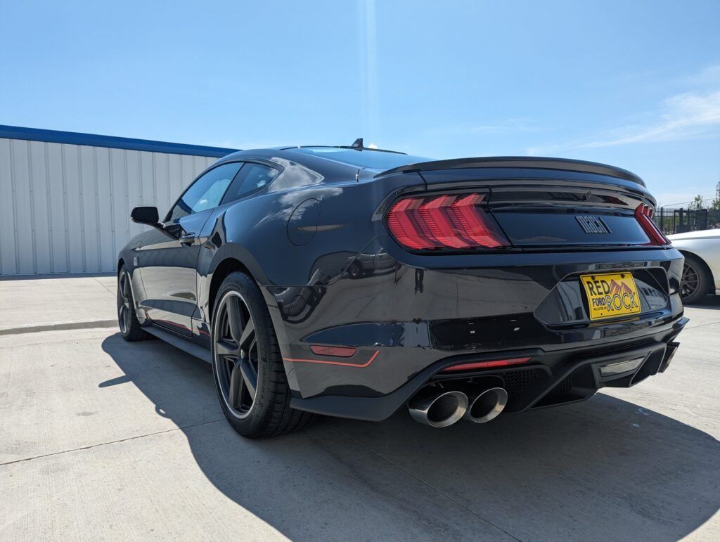 A black ford mustang is parked in front of a building.