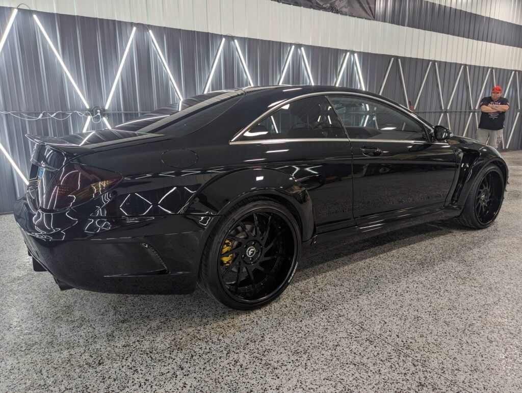 A black mercedes benz cls is parked in a garage.