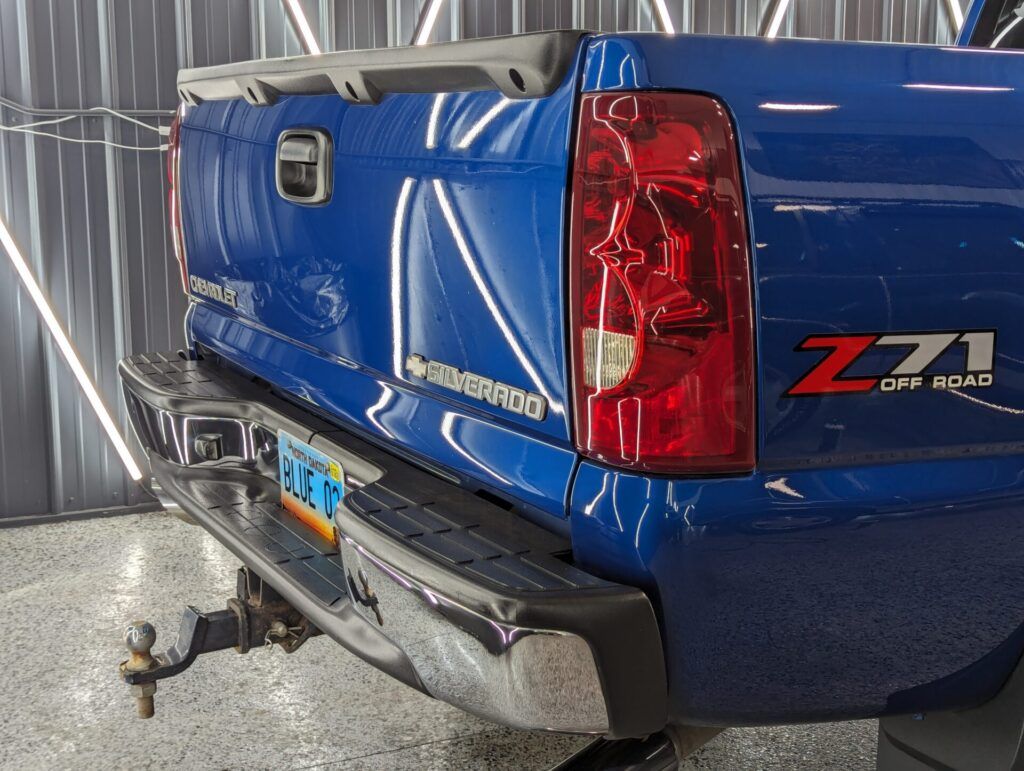 A blue truck with a red tail light is parked in a garage.