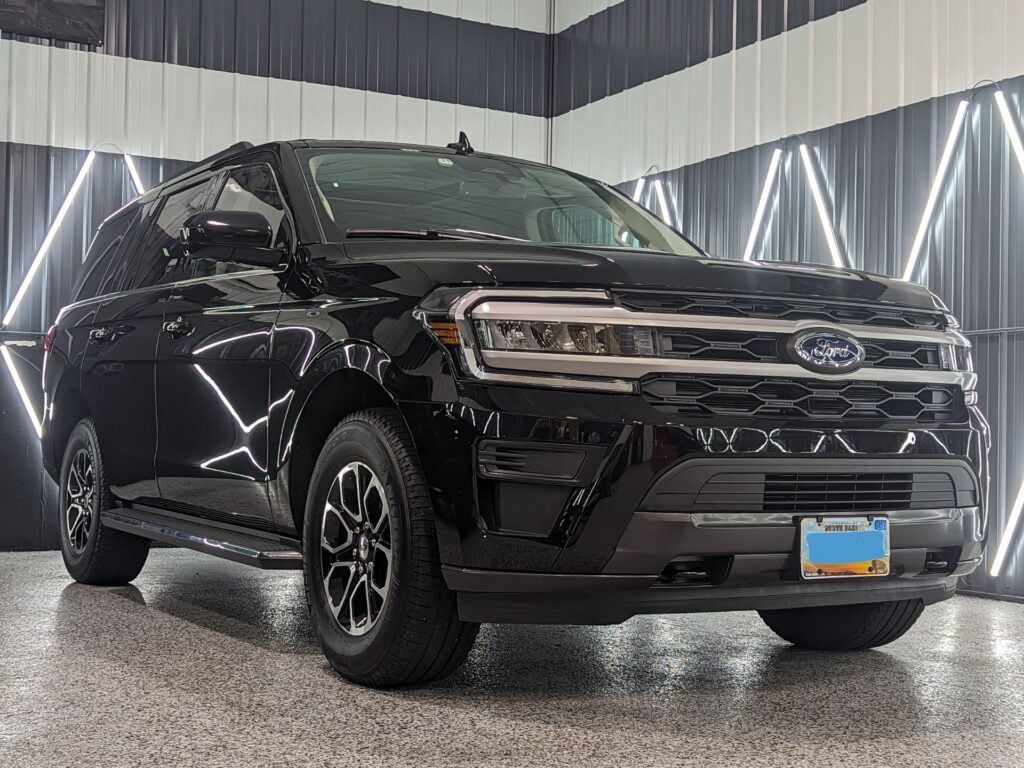 A black ford expedition is parked in a garage.