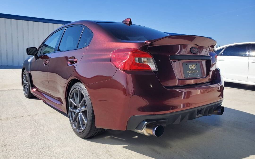 A red subaru wrx sti is parked in front of a building.