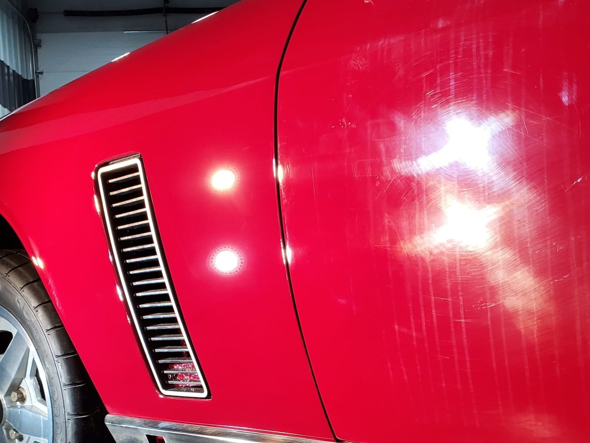 A red car is parked in a garage with the door open