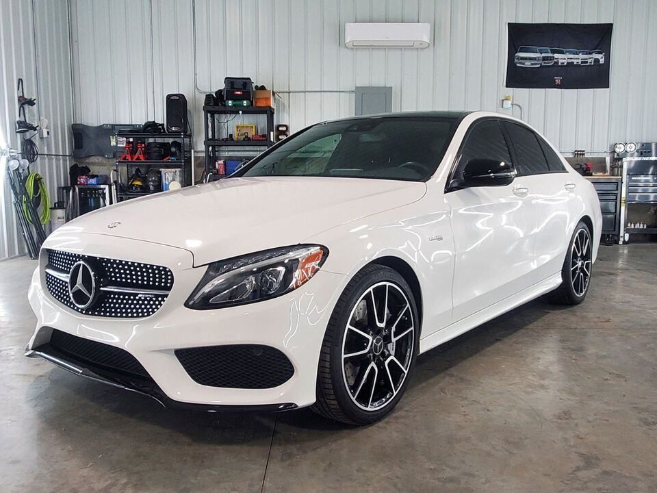 A white mercedes benz c class is parked in a garage.