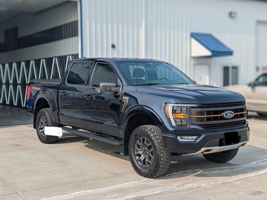 A black ford f150 truck is parked in front of a building.