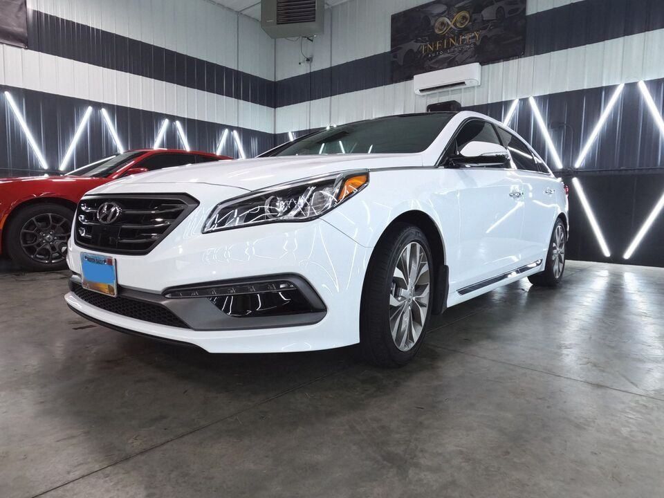 A white hyundai sonata is parked in a garage.