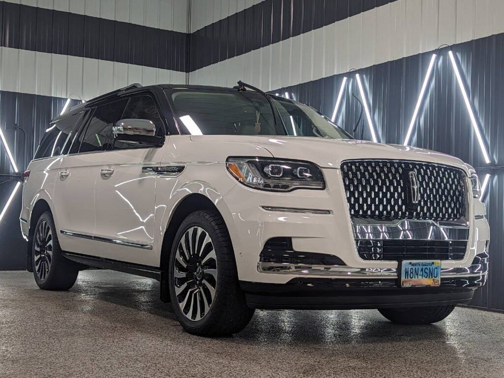 A white lincoln navigator is parked in a showroom.