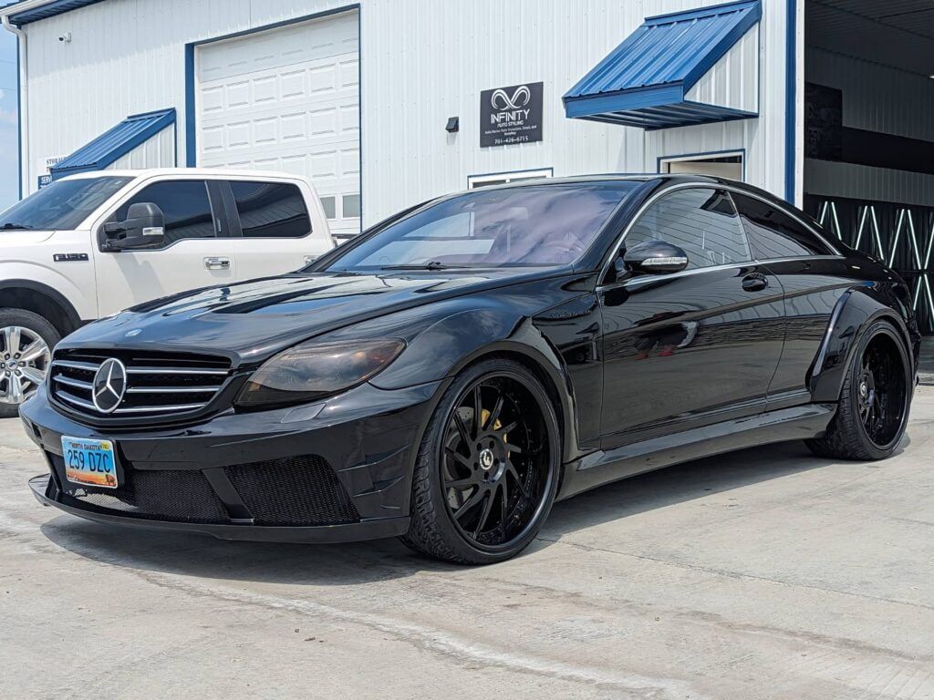 A black mercedes benz is parked in front of a garage.