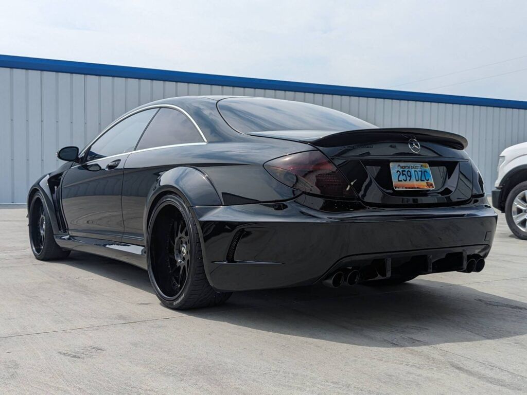 A black car with a new york license plate is parked in a parking lot.