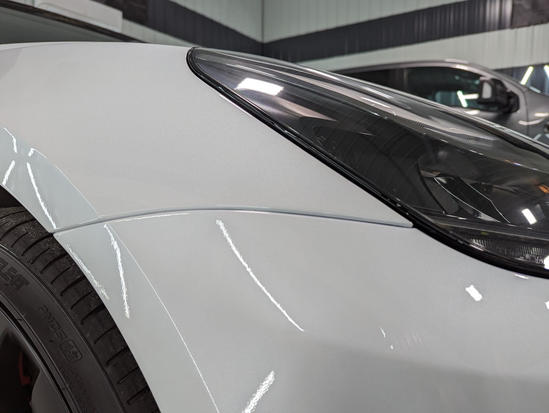 A close up of a white car 's headlight in a garage.