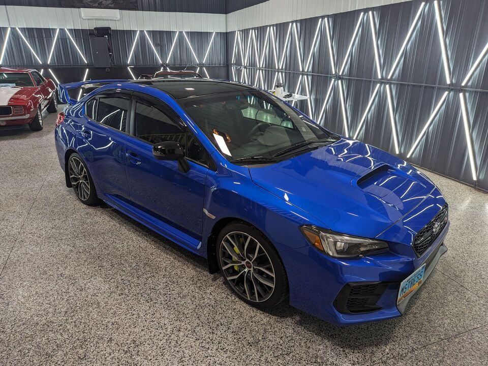 A blue subaru wrx sti is parked in a showroom.