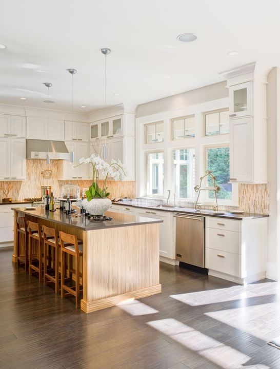 A kitchen with white cabinets , stainless steel appliances , and a large island.