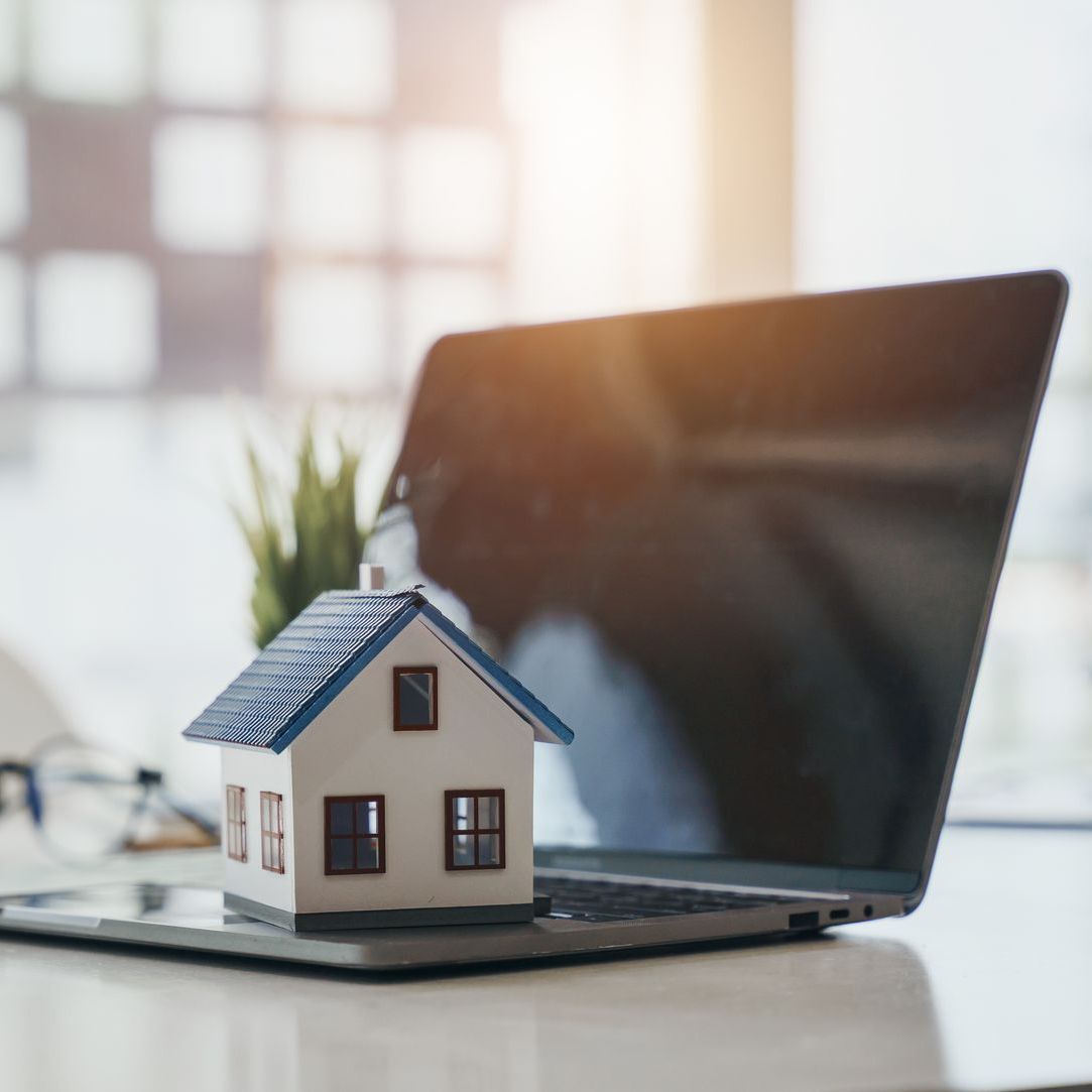 A model house is sitting on top of a laptop computer
