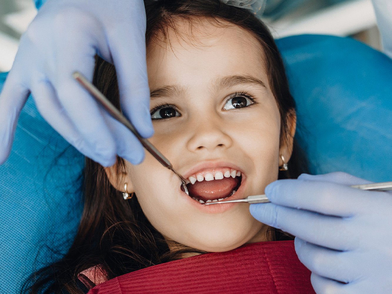 young child smiling while getting teeth examined
