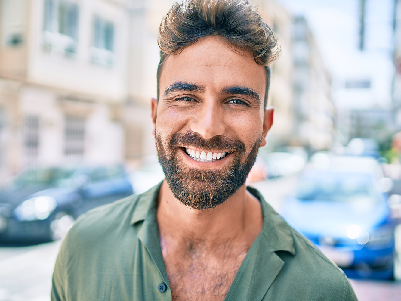 Guy smiling outside teeth showing in front of building