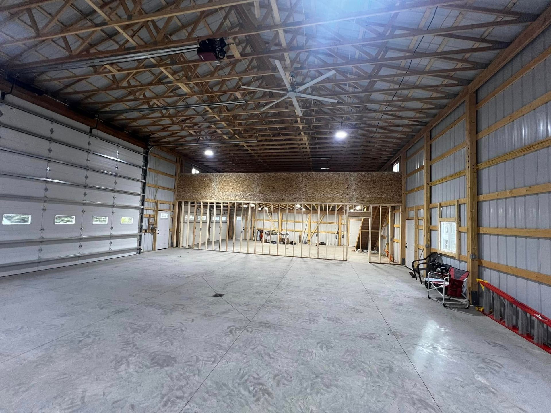 Empty warehouse interior with concrete floor, unfinished walls, and wood framing.