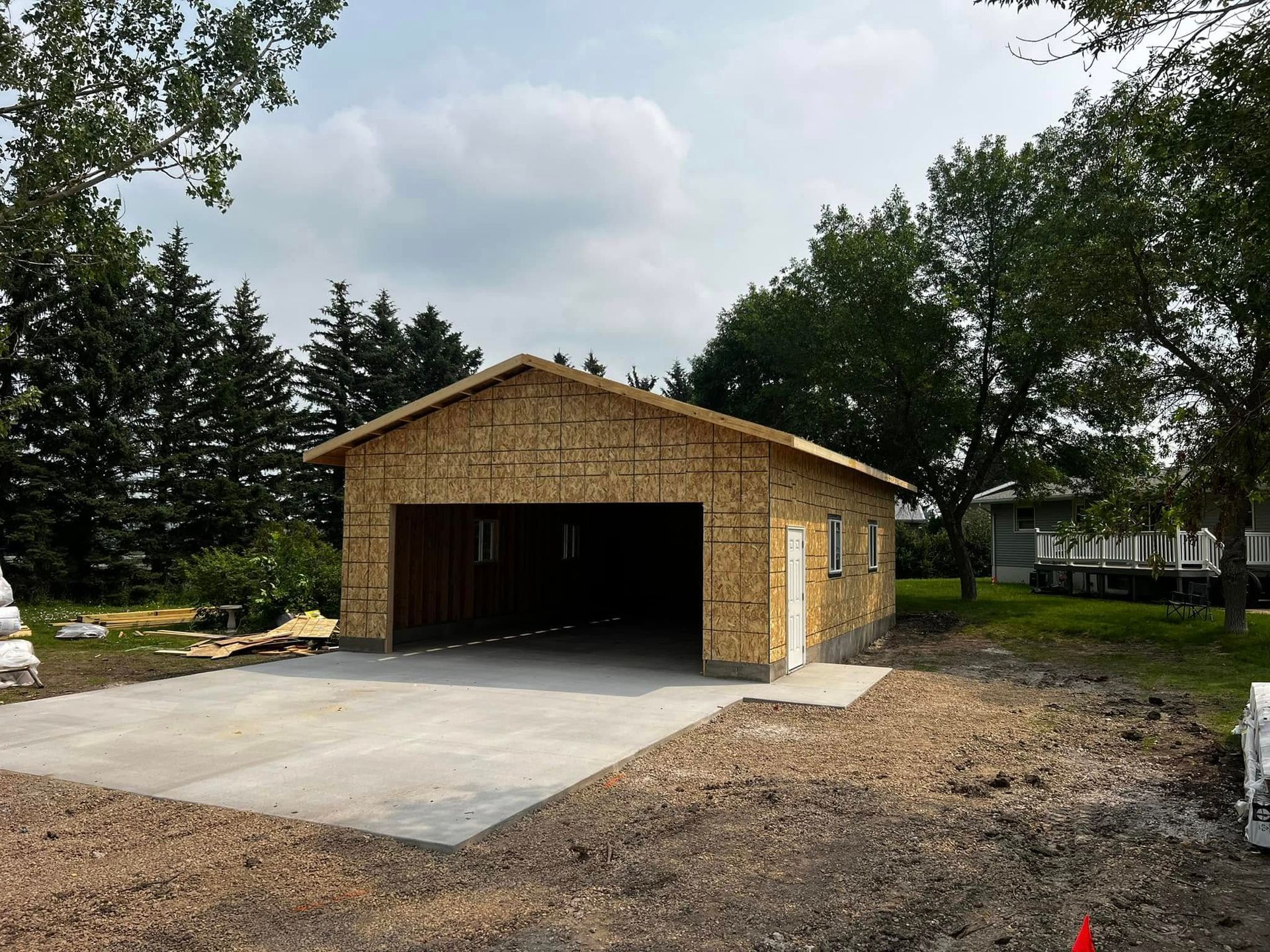 Garage under construction with concrete driveway. Exterior walls are sheathed.