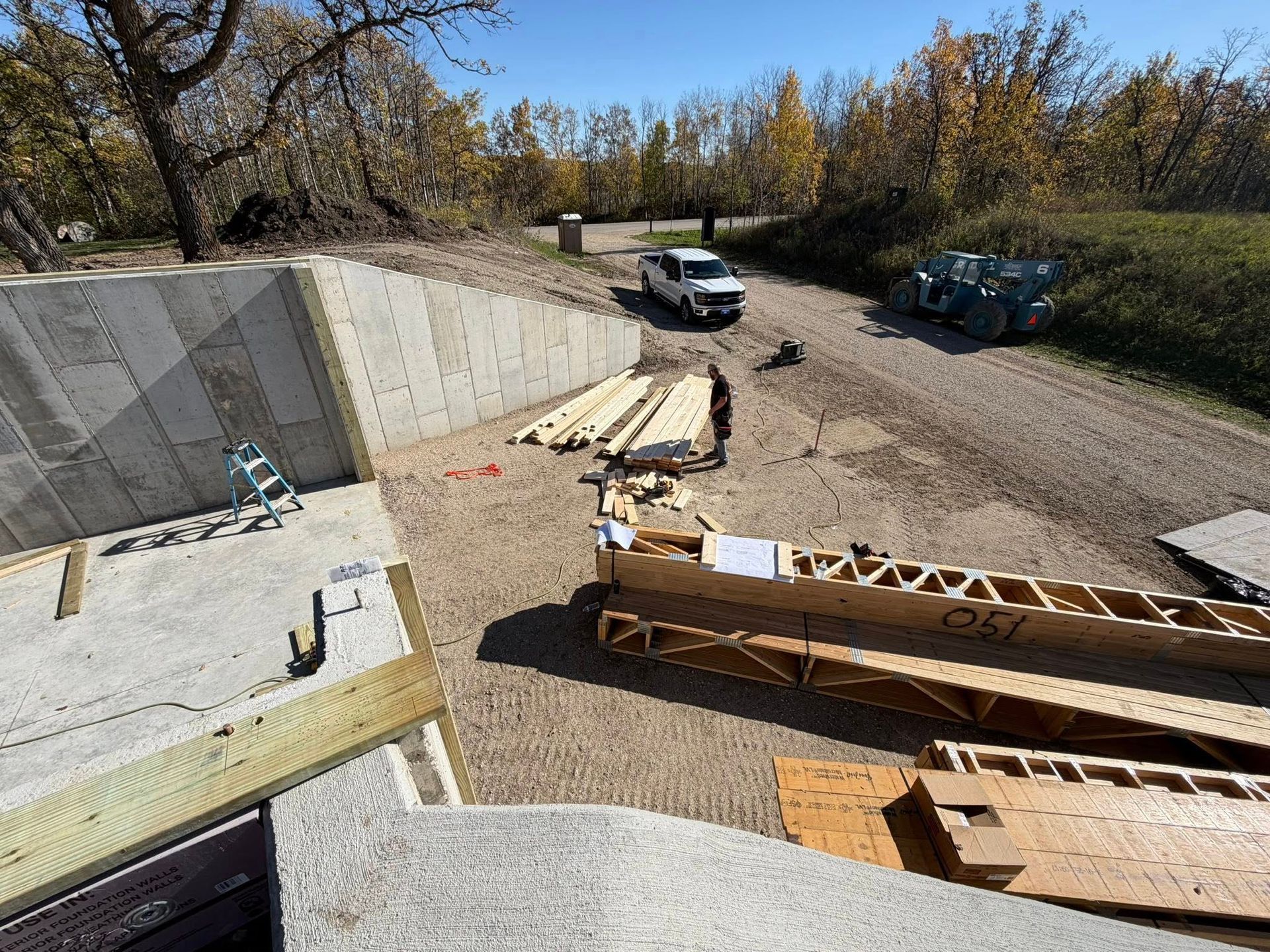 Construction site: concrete walls, wood beams, truck on dirt road.