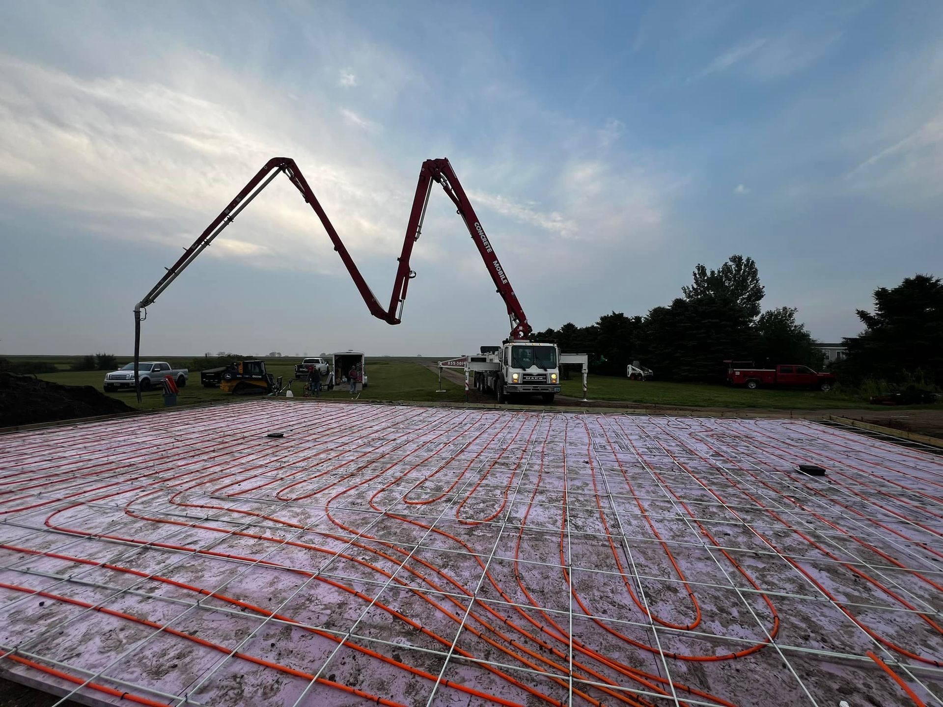 Concrete being poured onto a radiant floor system from a pump truck, outdoors.