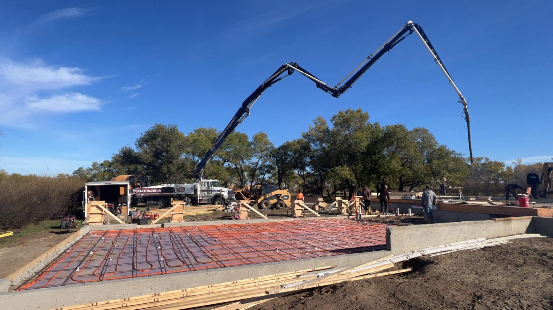 Concrete pump truck pouring concrete into a prepared foundation on a construction site.