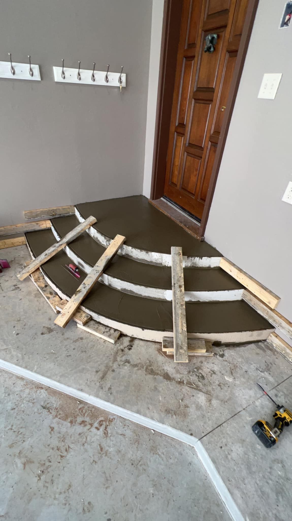Concrete being poured for curved entryway. Wooden frame guides the wet cement.
