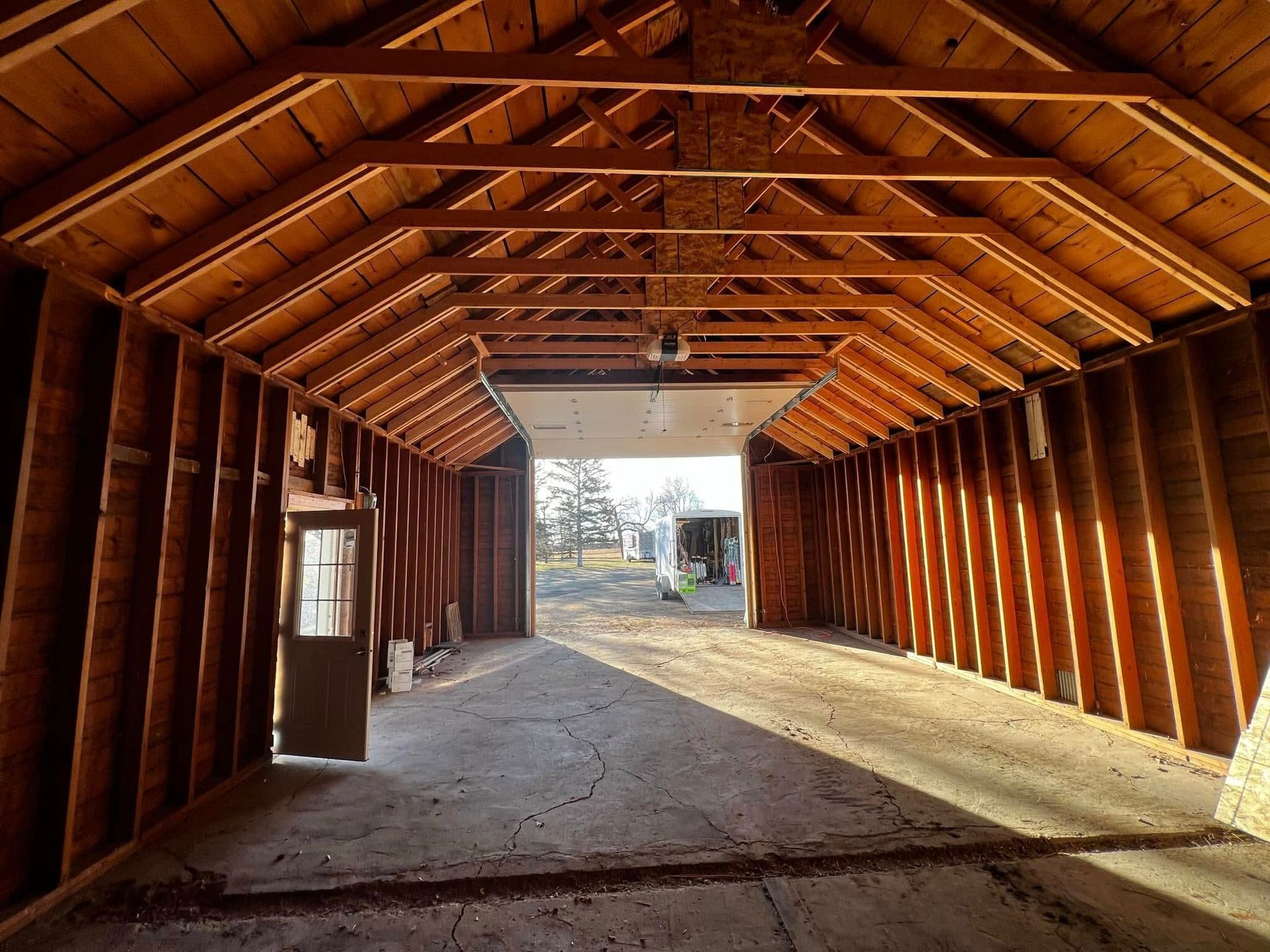 Interior of a wooden garage with open doors, sunlight streaming in.