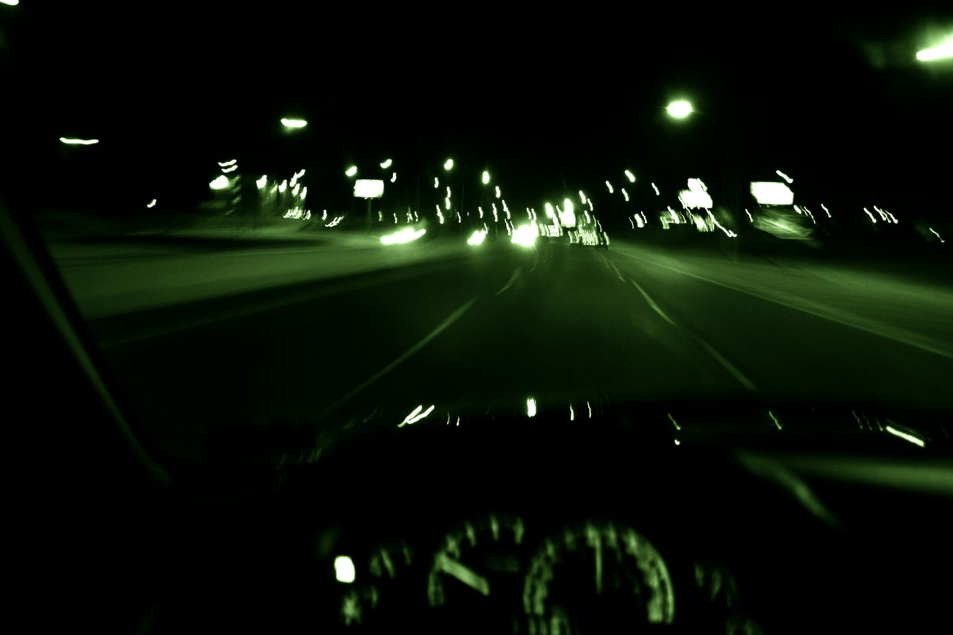 Nighttime highway view from inside a car, blurred streaks of light.