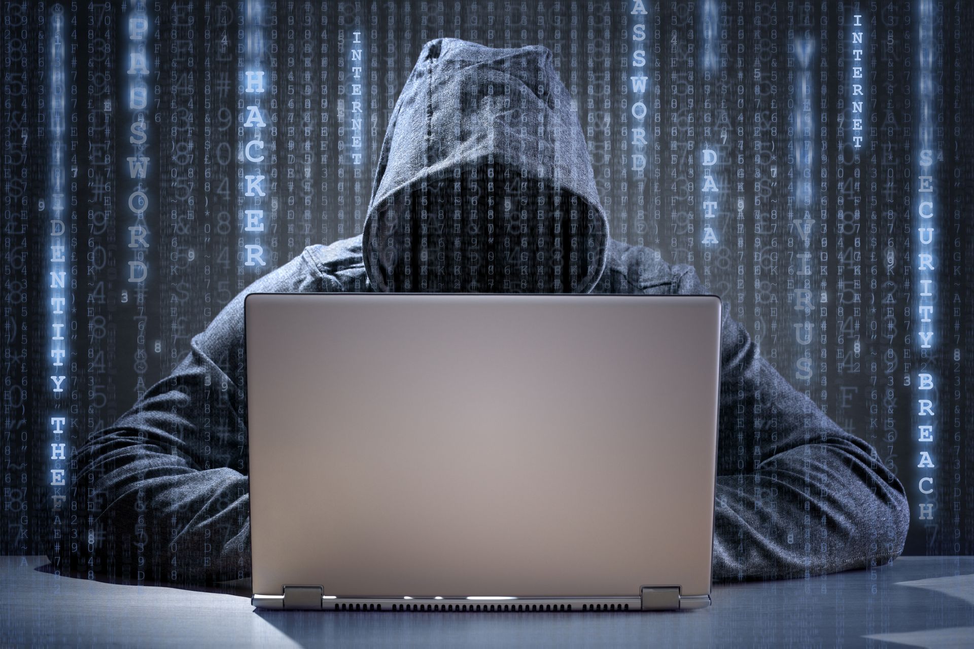 Person in hoodie using a laptop, with a matrix-style background, suggesting a hacker.