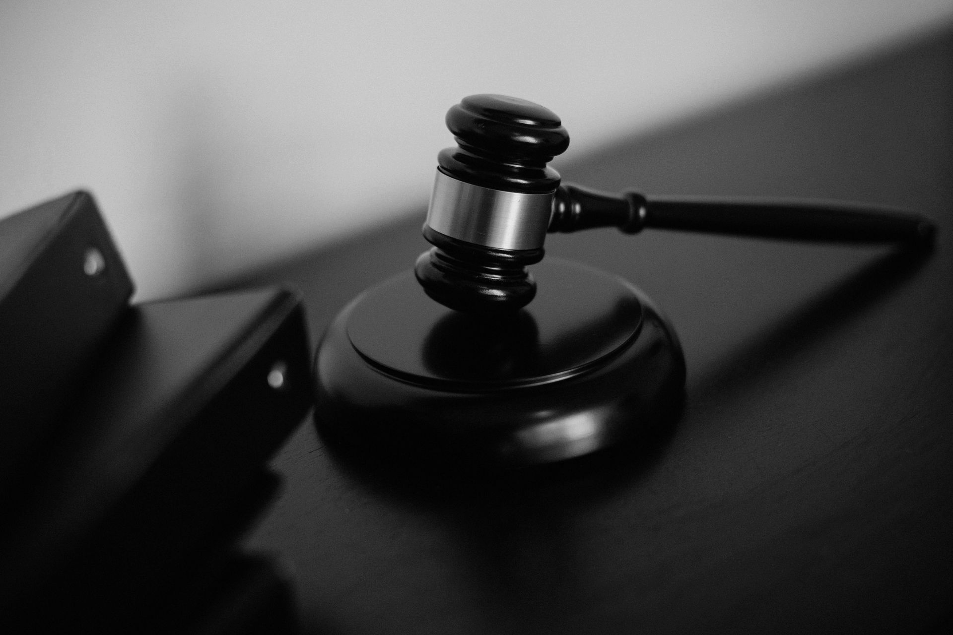 Black and white photo of a gavel on its stand on a dark surface.