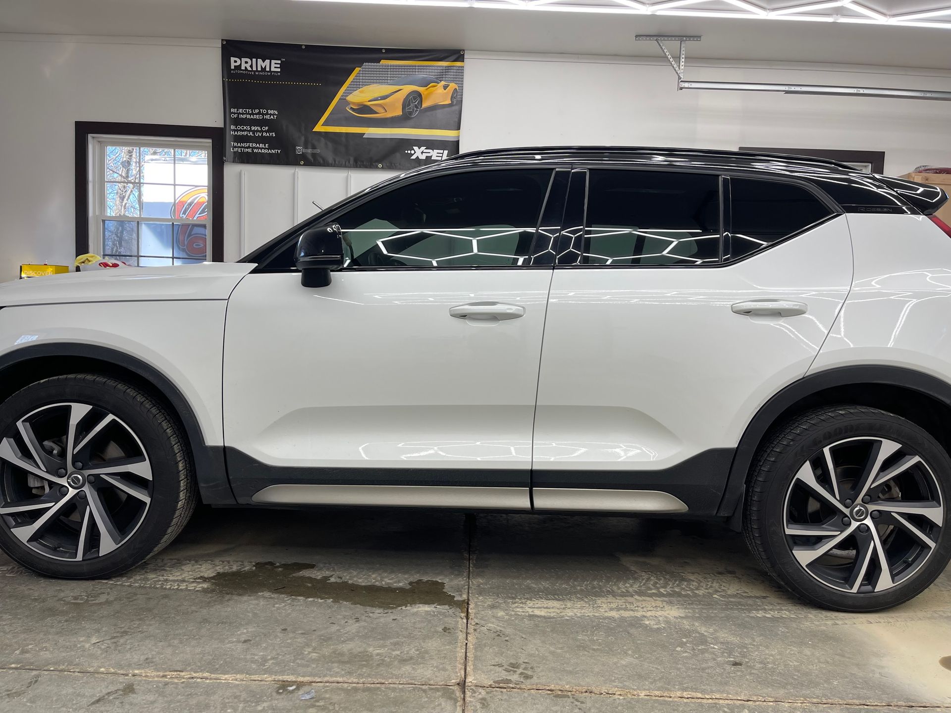 White Volvo SUV with tinted windows, parked in a garage.