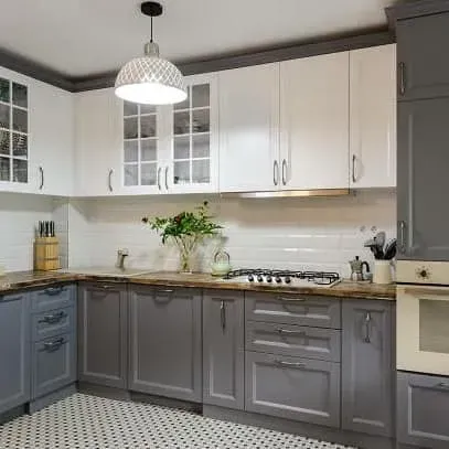 Kitchen with white and grey cabinets, a stove, and pendant light.